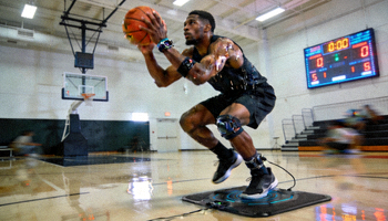 专业篮球运动员在训练馆使用谈球吧智能装备进行高强度训练的场景